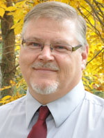 Middle aged man wearing a shirt and tie.