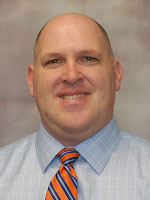 Middle aged man wearing a light colored shirt and tie.