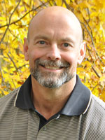 Middle aged man wearing a tan shirt.